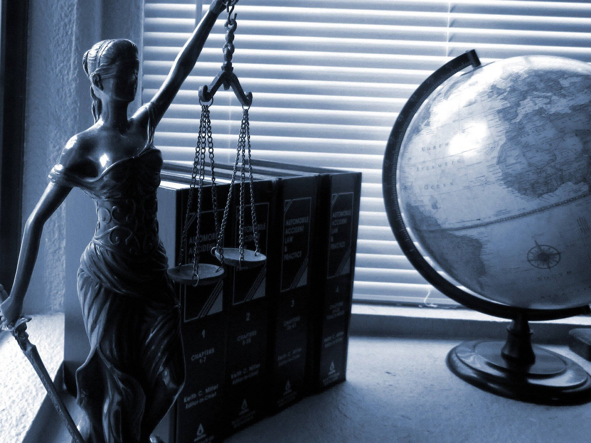 Lady Justice with scale and a globe on a desk in blue scale